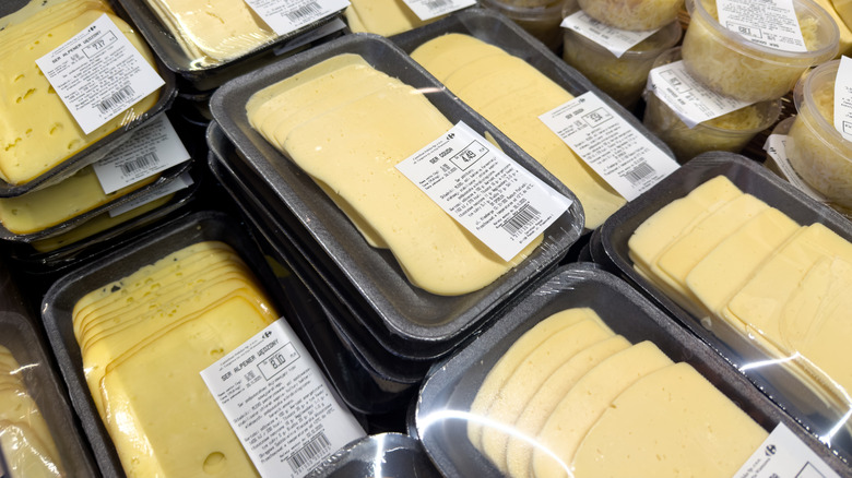 Packaged trays of sliced, white cheese in a deli