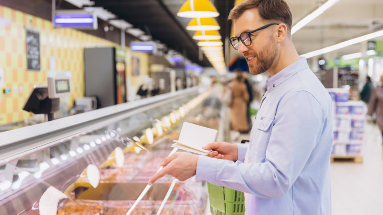 man holding notebook while pointing to something in the deli counter