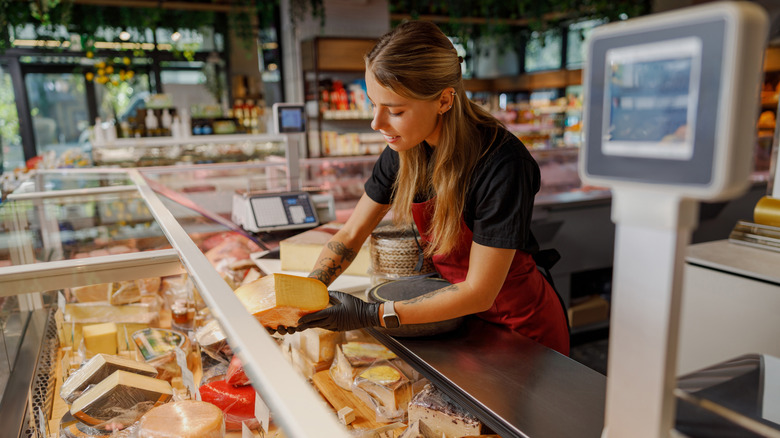 deli worker picking up cheese at the deli counter