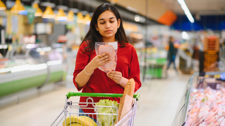 Woman in grocery store checking package of deli meat