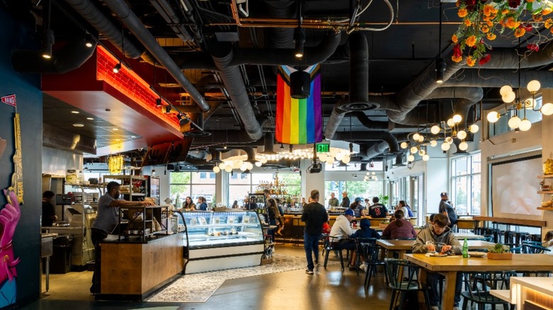 The inside of a restaurant with flowers and wooden tables