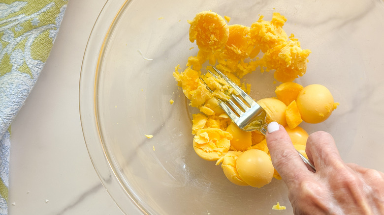 hand mashing egg yolks with fork
