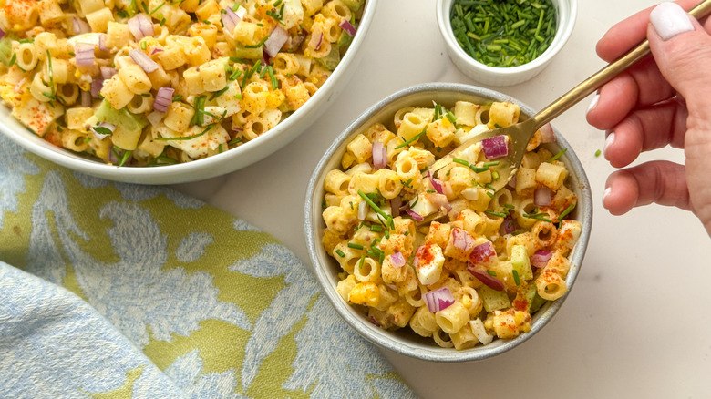 hand with fork in bowl of deviled egg pasta salad