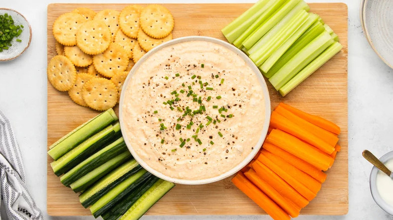 Deviled egg party dip with veggies sticks and crackers on wooden board