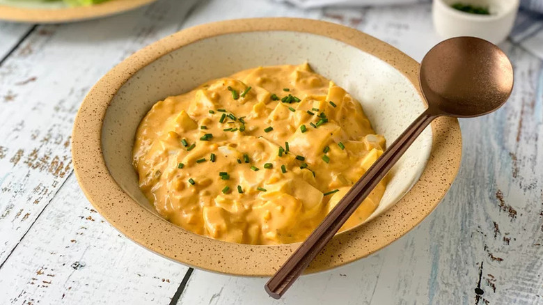 Deviled Egg Salad in beige bowl with gold spoon