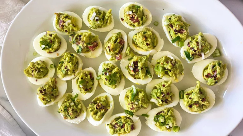 Top-view image of guacamole deviled eggs on white plate