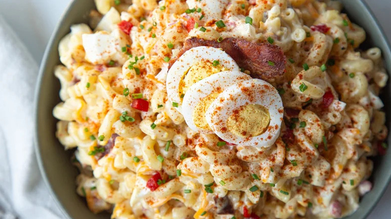 Close-up image of loaded deviled egg pasta salad in blue bowl