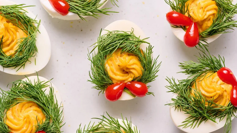 Top view of holiday-themed deviled eggs with dill wreaths and tiny peppers