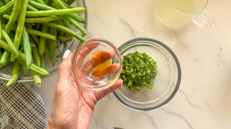 hand adding oil to bowl