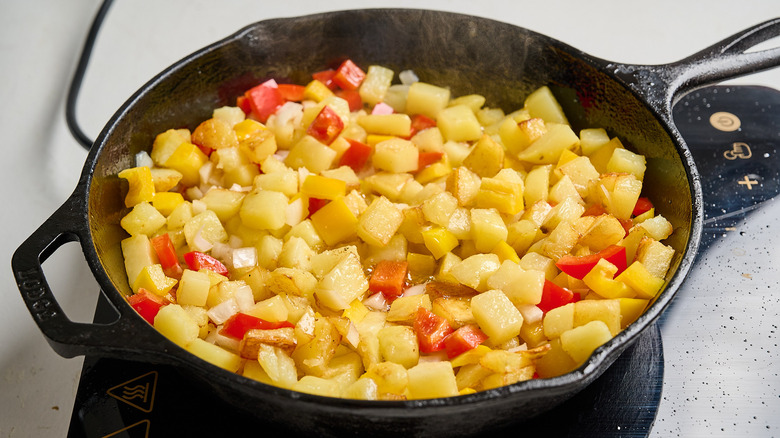 peppers and onions in a skillet with potatoes