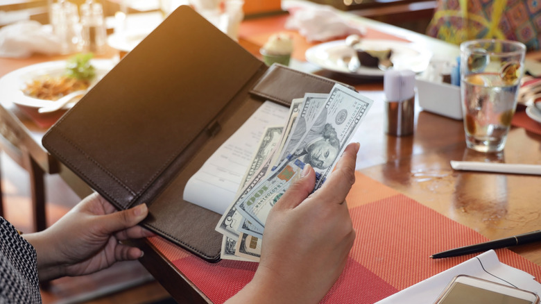 Restaurant patron's hands holding bill and cash