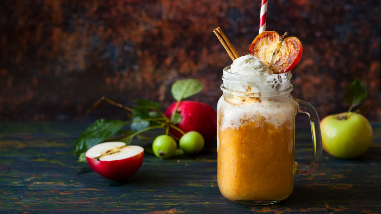 Dirty apple cider is served in a jar and topped with ice cream and an apple slice.