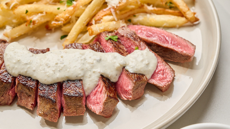 side view of steak on a plate covered in blue cheese dressing