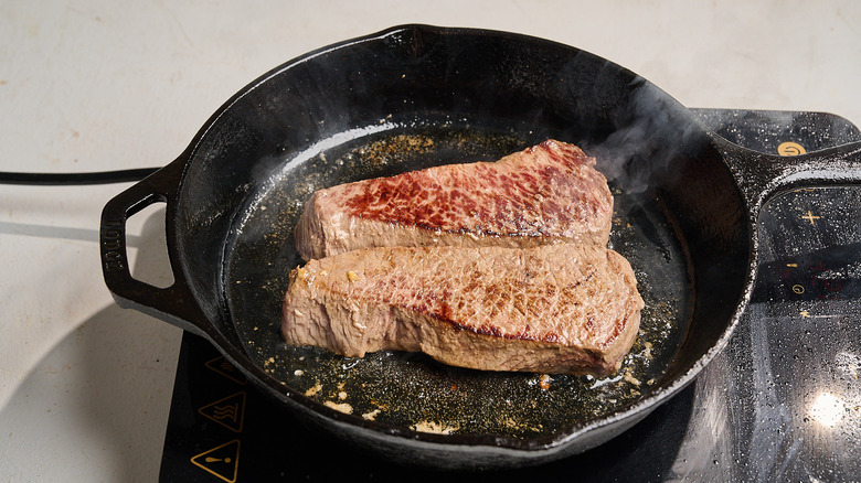 cooking steaks in a cast iron skillet