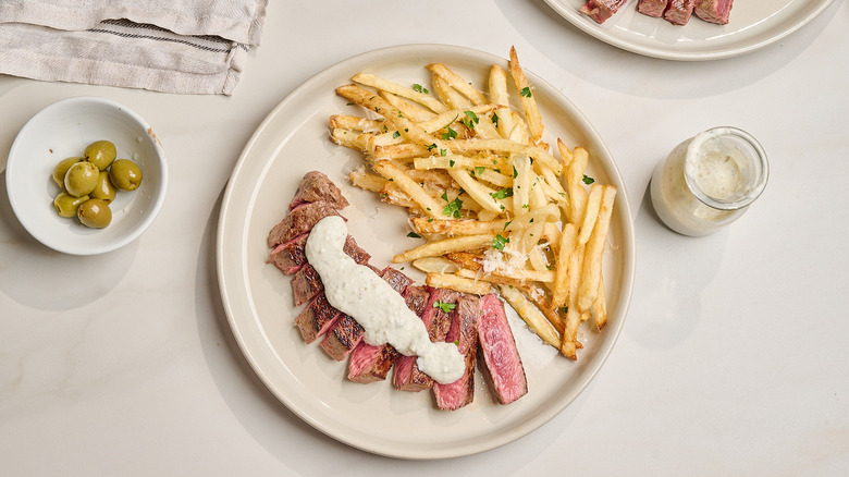 sliced steak on a plate with french fries