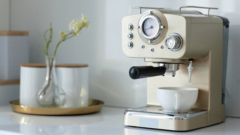 A gold espresso machine in front of a white wall