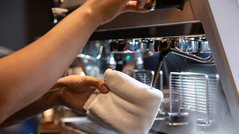close up of a person cleaning the milk frother on an espresso machine