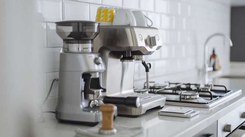 An espresso machine sits on a counter near a built-in stovetop