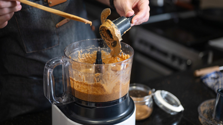 A person using a food processor with messy ingredients.