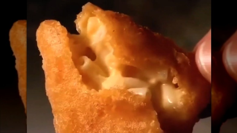 Hands opening a Jack in the Box cheesy macaroni bite