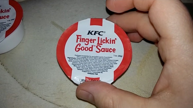 Hand holding package of KFC  Finger Lickin' Good sauce