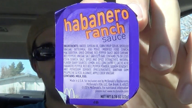 Hand holding up a container of McDonald's Habanero Ranch Sauce