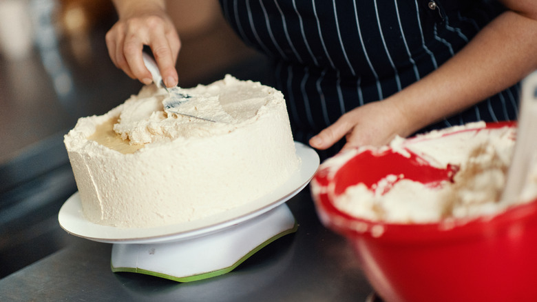 Person adding icing to a cake