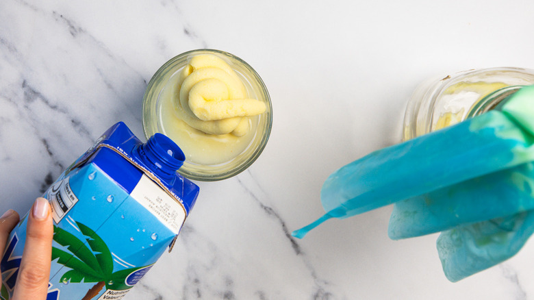 Adding coconut water to Dole Whip ice cream in a glass.