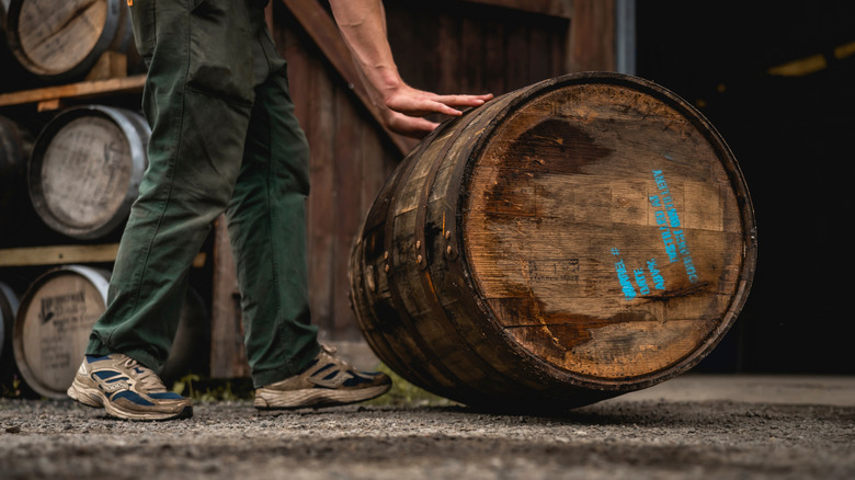 A person rolling barrel with distillery information showed stamped on the lid