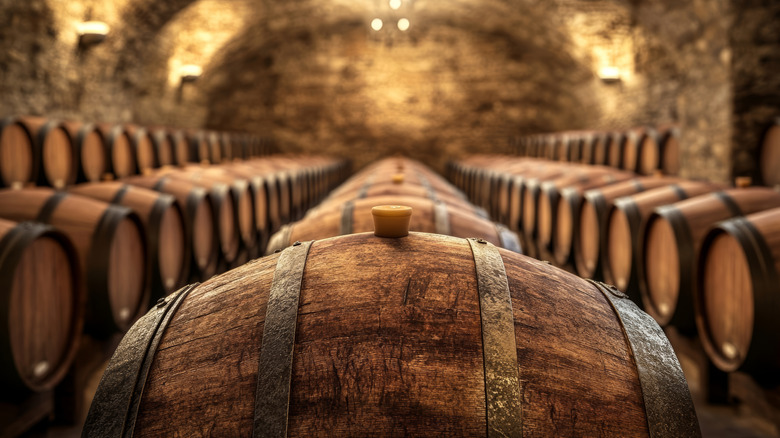 A brick cellar with rows of barrels with a closeup shot of one with the rest in a blurred background