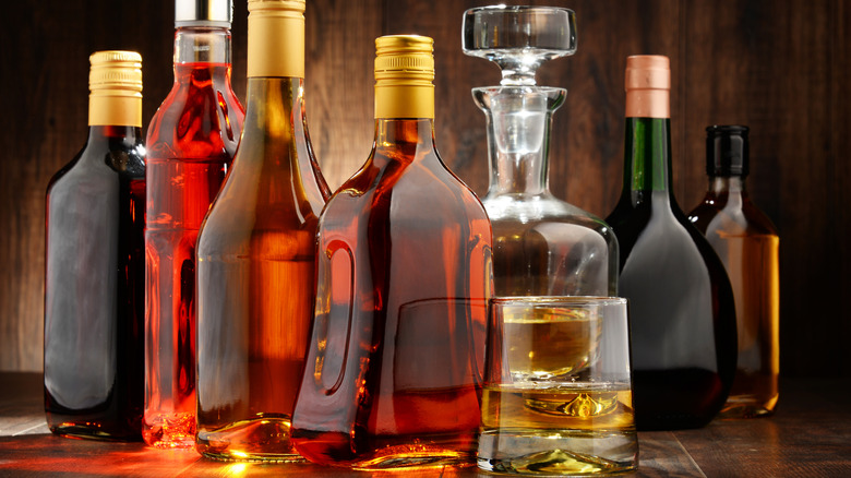 A wide range of unbranded spirit bottles without labels with a filled glass in the foreground