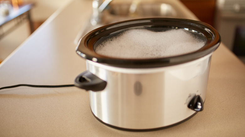 A slow cooker filled with soapy water