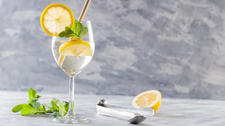 An ice cold Hugo spritz in a wine glass of ice with mint and lemon