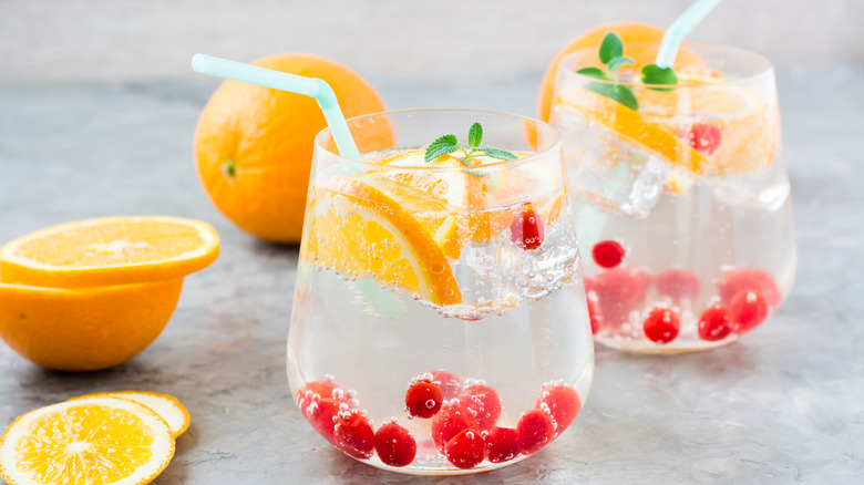 Two glasses of hard seltzer with orange slices, berries