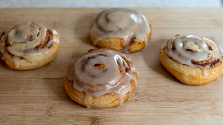 Cinnamon rolls coated in a simple glaze sitting on a wooden counter