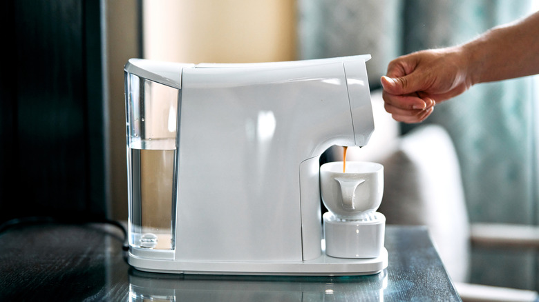 White single-serve coffee machine pouring coffee into a white mug.