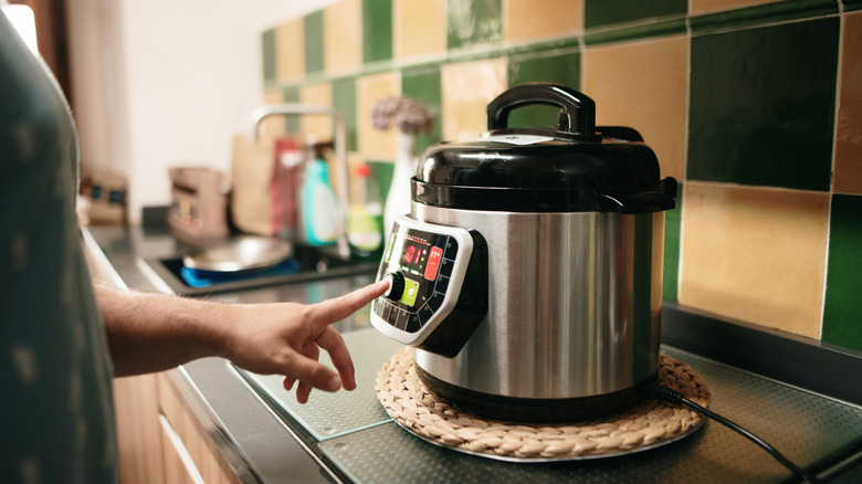 A person presses a button on a multicooker