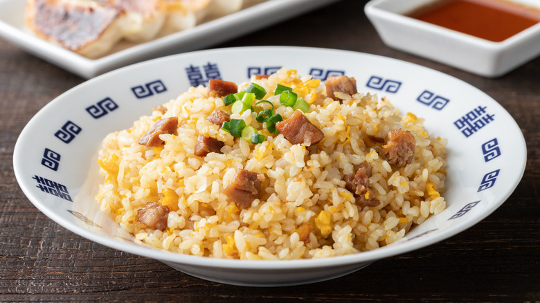 Asian fried rice in bowl with brown sauce in background