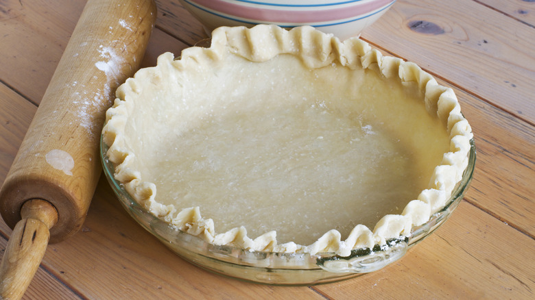 Pie crust with rolling pin on a wooden table