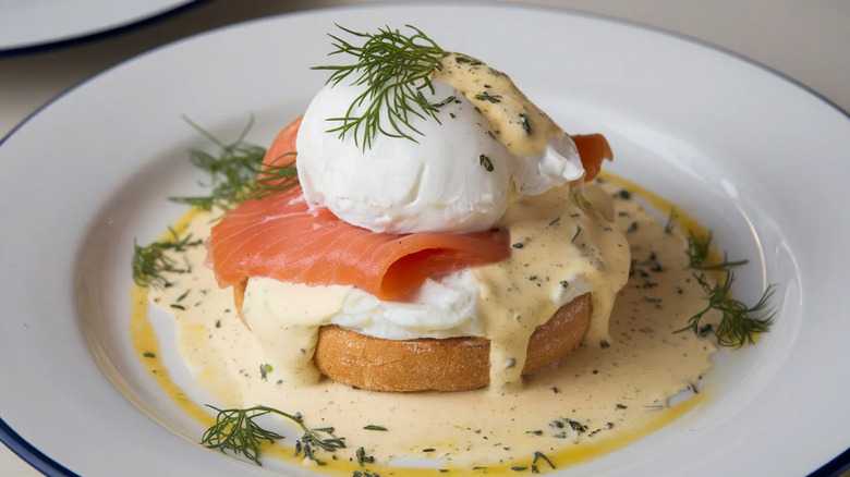 A plate of Norwegian eggs Benedict with smoked salmon topped with dill