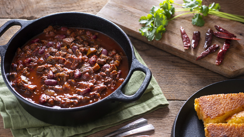 A cast-iron pot of chili with corn bread on the side.