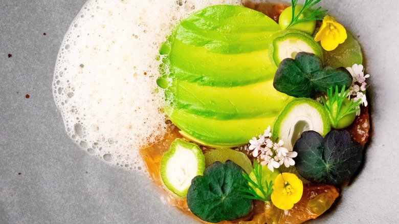 Avocado slices with foam and edible flowers at Lazy Bear