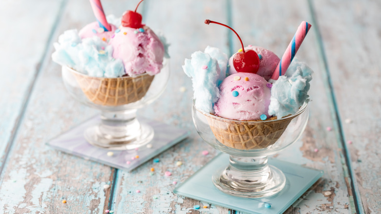 two glass cups with cotton candy ice cream, whipped cream, and a cherry