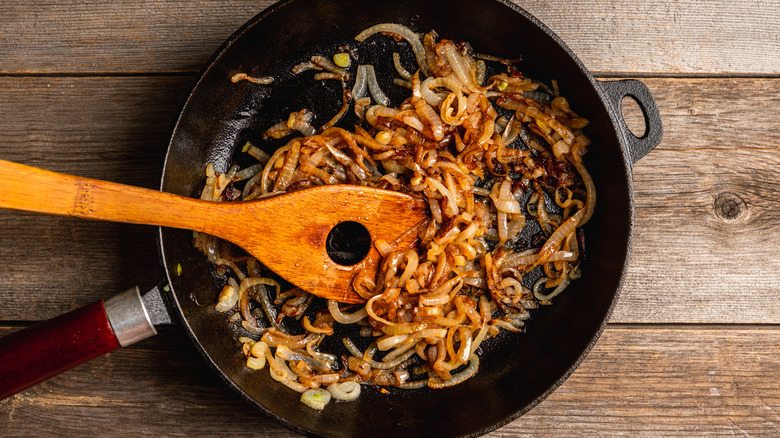 A pan of fully caramelized onions and a wooden spatula