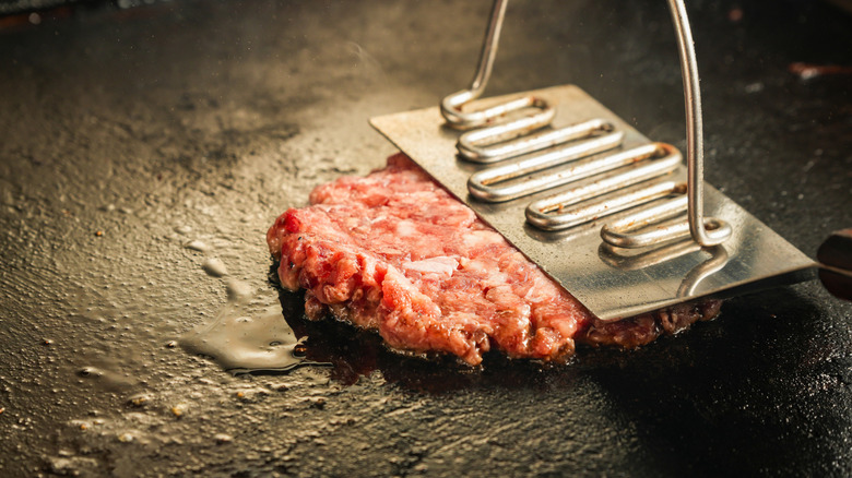 Smashed burger patty cooking on griddle