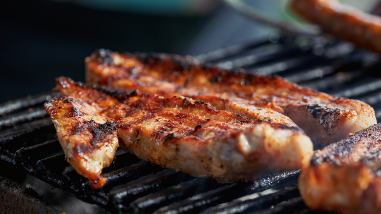 cooking pork and chicken on grill