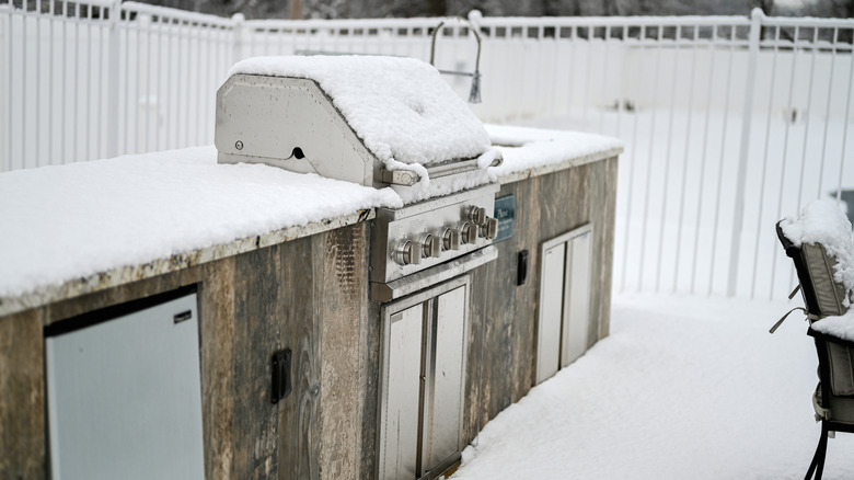 Grill covered in backyard with snow