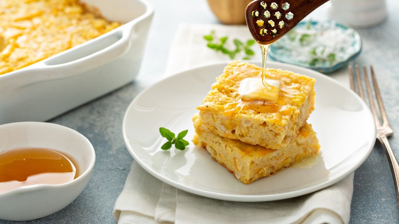 Freshly sliced piece of cheese cornbread with honey drizzled on top