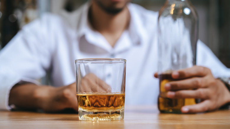 Person drinking whiskey at bar