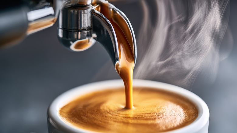 Espresso pouring from a portafilter with steam